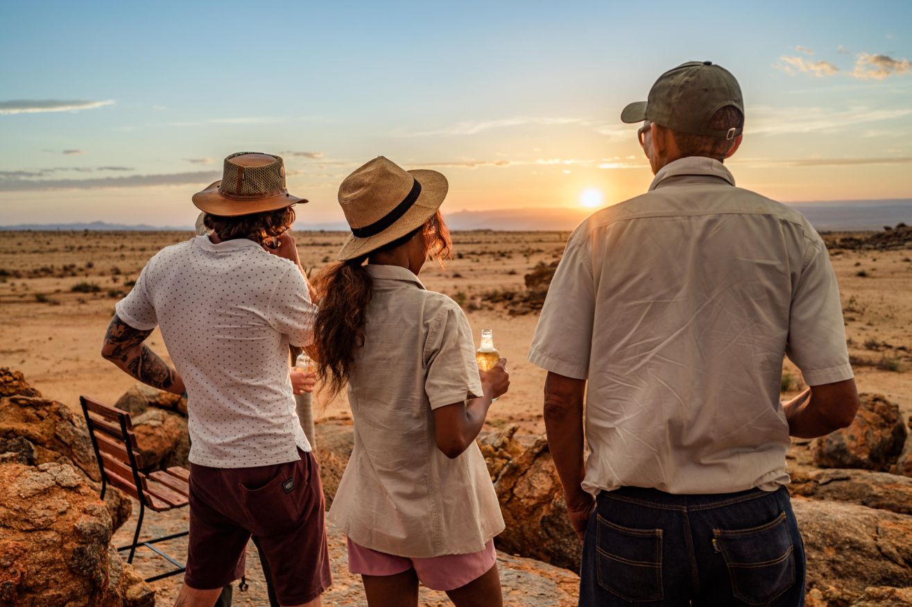 Travelers watching the sunset over the Namibian desert